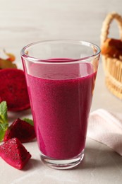 Photo of Delicious pitahaya smoothie and fresh fruits on light grey table