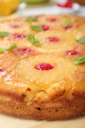 Photo of Tasty pineapple cake with cherries and mint on table, closeup