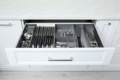 Photo of Open drawer with stainless steel utensil set. Order in kitchen