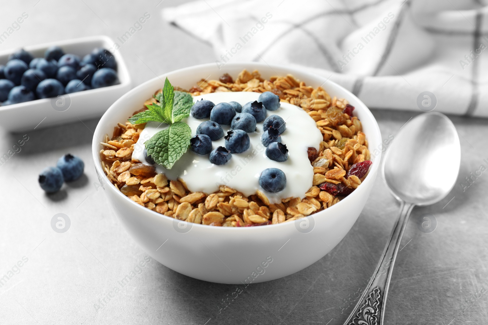 Photo of Delicious yogurt with granola and blueberries served on grey table