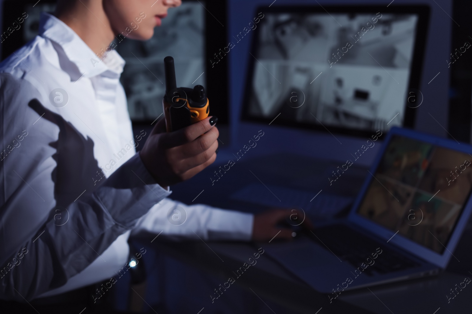 Photo of Female security guard with portable transmitter monitoring home cameras indoors at night, closeup