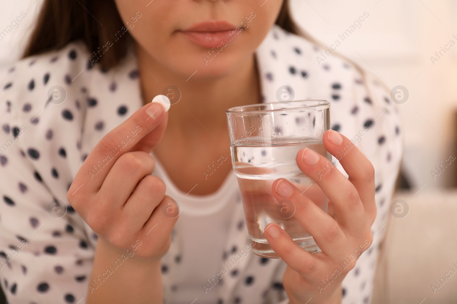 Photo of Young woman taking abortion pill indoors, closeup