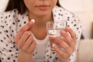 Photo of Young woman taking abortion pill indoors, closeup