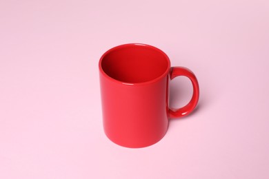 Photo of One red ceramic mug on pink background