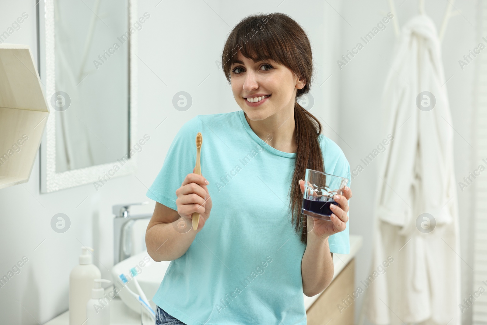 Photo of Young woman with mouthwash and toothbrush in bathroom