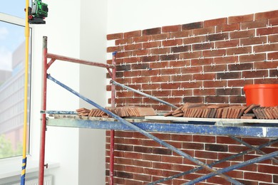 Photo of Scaffolding near wall with decorative bricks and tile leveling system indoors