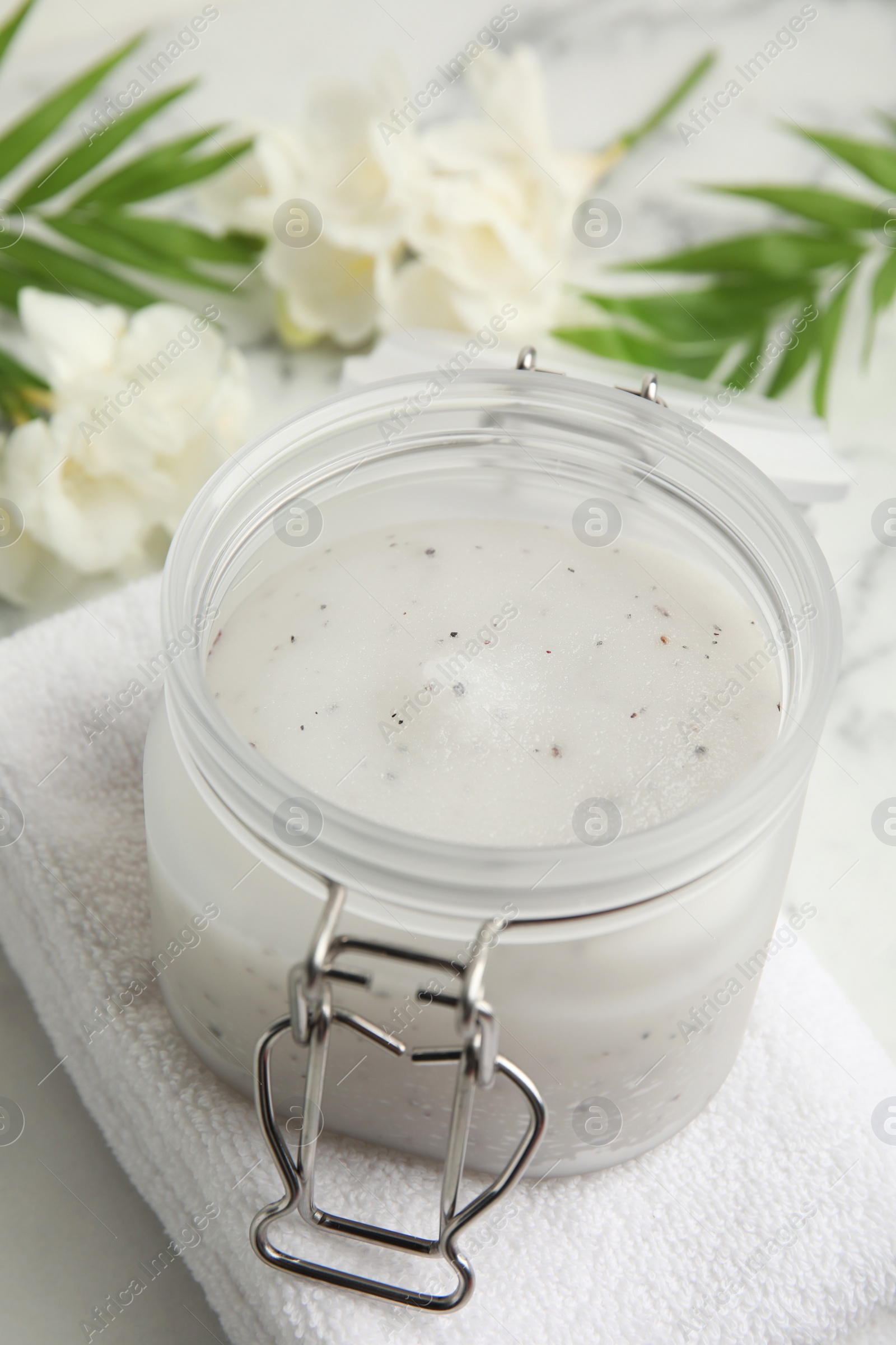 Photo of Jar of salt scrub and towel on white table