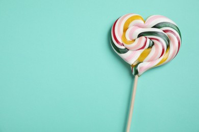 Photo of Stick with heart shaped lollipop on turquoise background, top view. Space for text