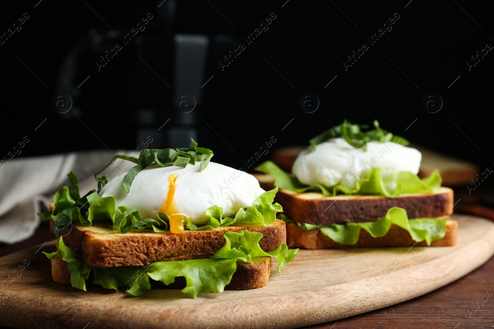 Photo of Delicious poached egg sandwiches served on wooden board