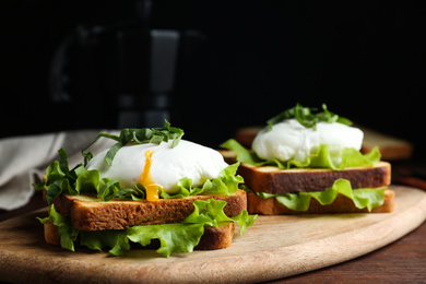 Photo of Delicious poached egg sandwiches served on wooden board