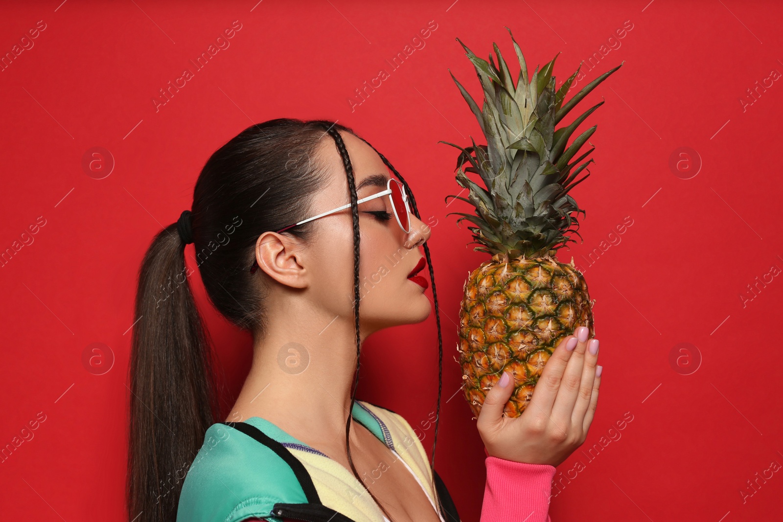 Photo of Young woman with fresh pineapple on red background. Exotic fruit