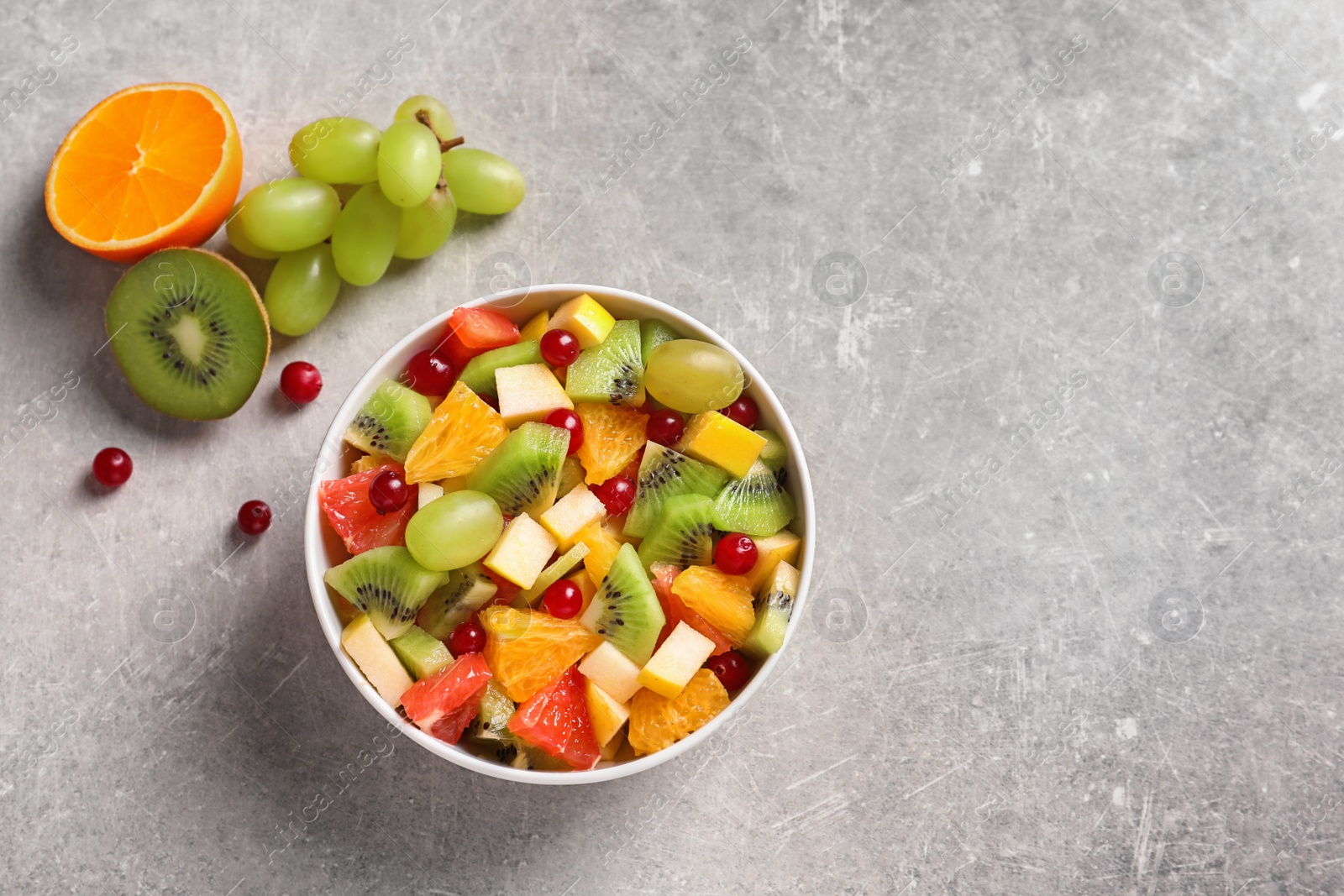 Photo of Bowl with fresh fruit salad on grey background