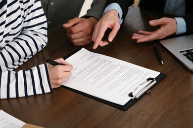 Notary working with couple at wooden table, closeup