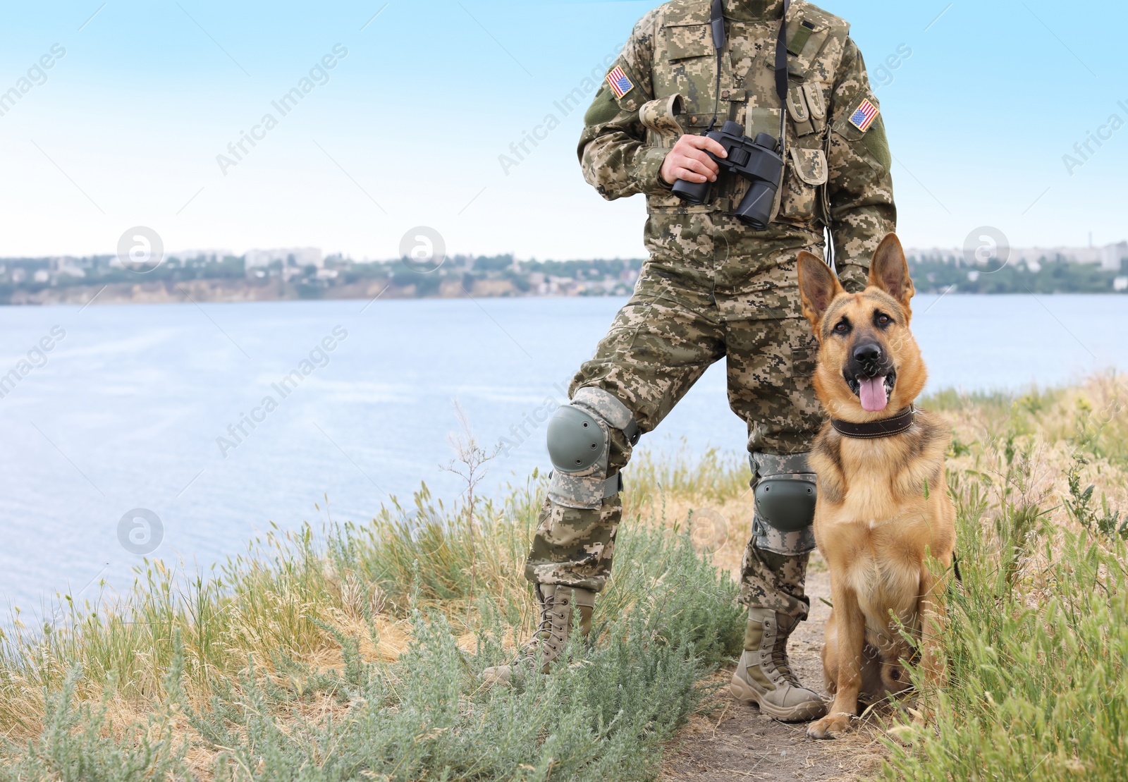 Photo of Man in military uniform with German shepherd dog near river