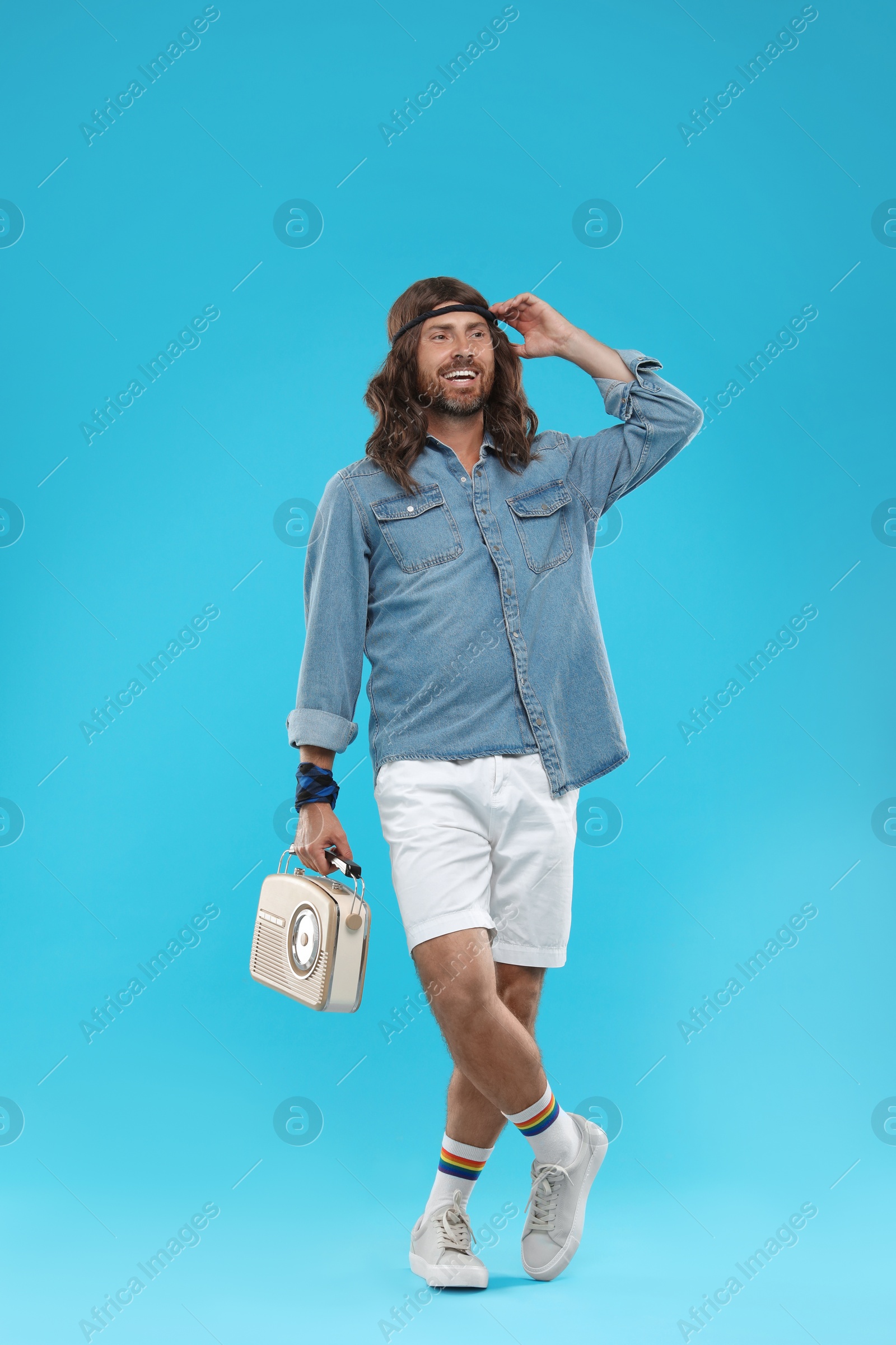 Photo of Stylish hippie man with retro radio receiver on light blue background