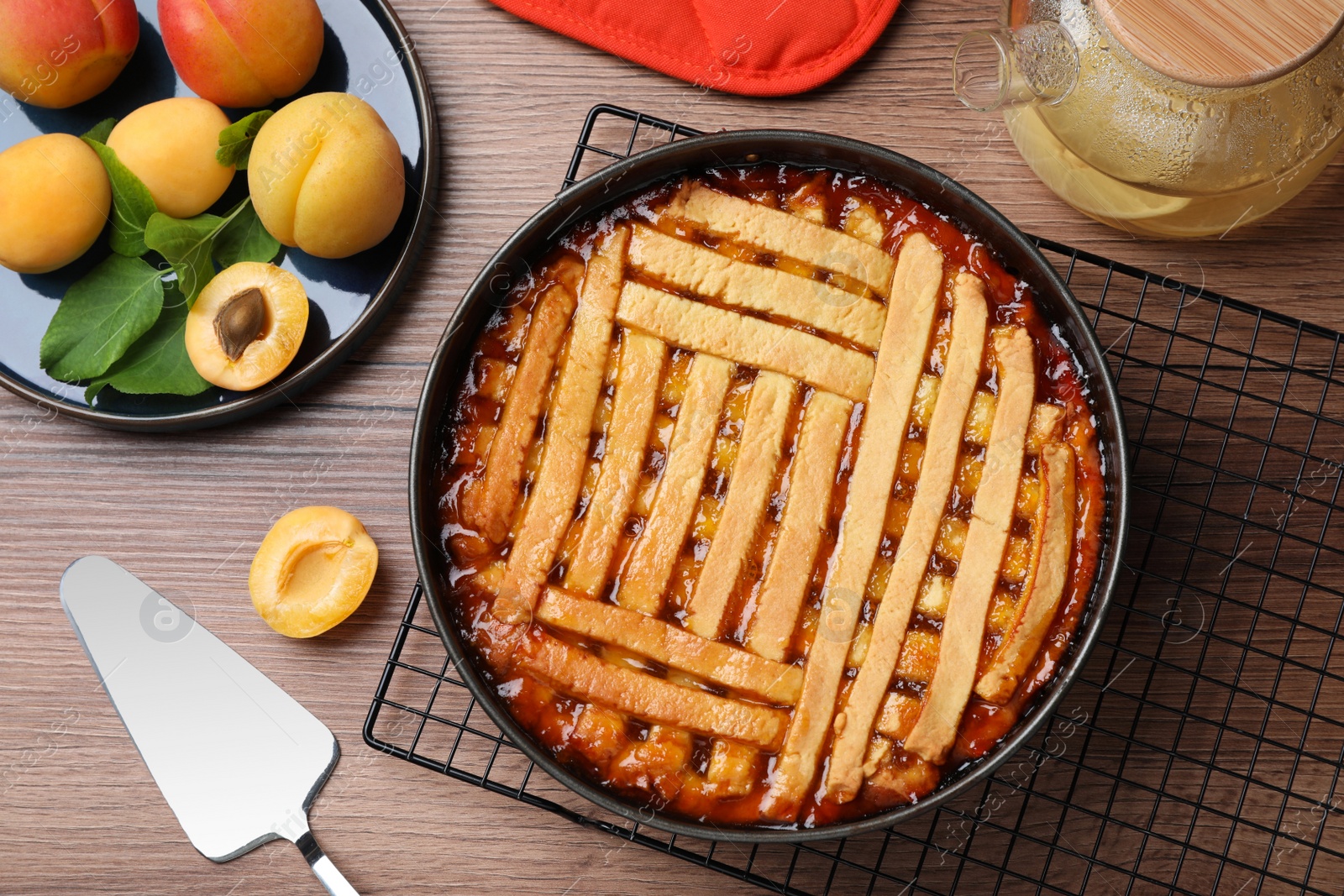 Photo of Delicious apricot pie in baking dish and fresh fruits on wooden table, flat lay