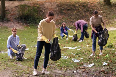 Photo of Group of people with plastic bags collecting garbage in park