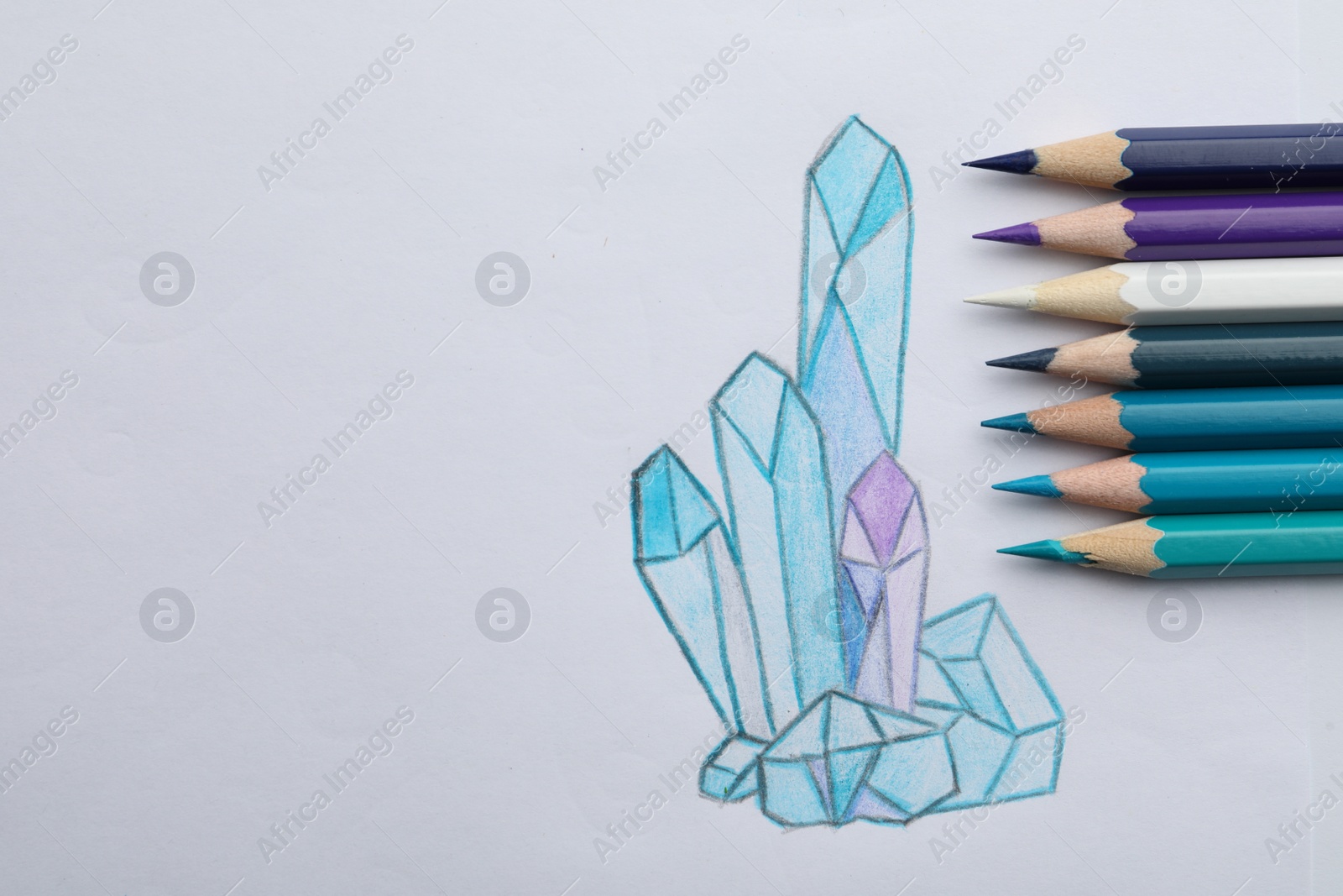 Photo of Drawing of crystals and colorful pencils on white background, top view