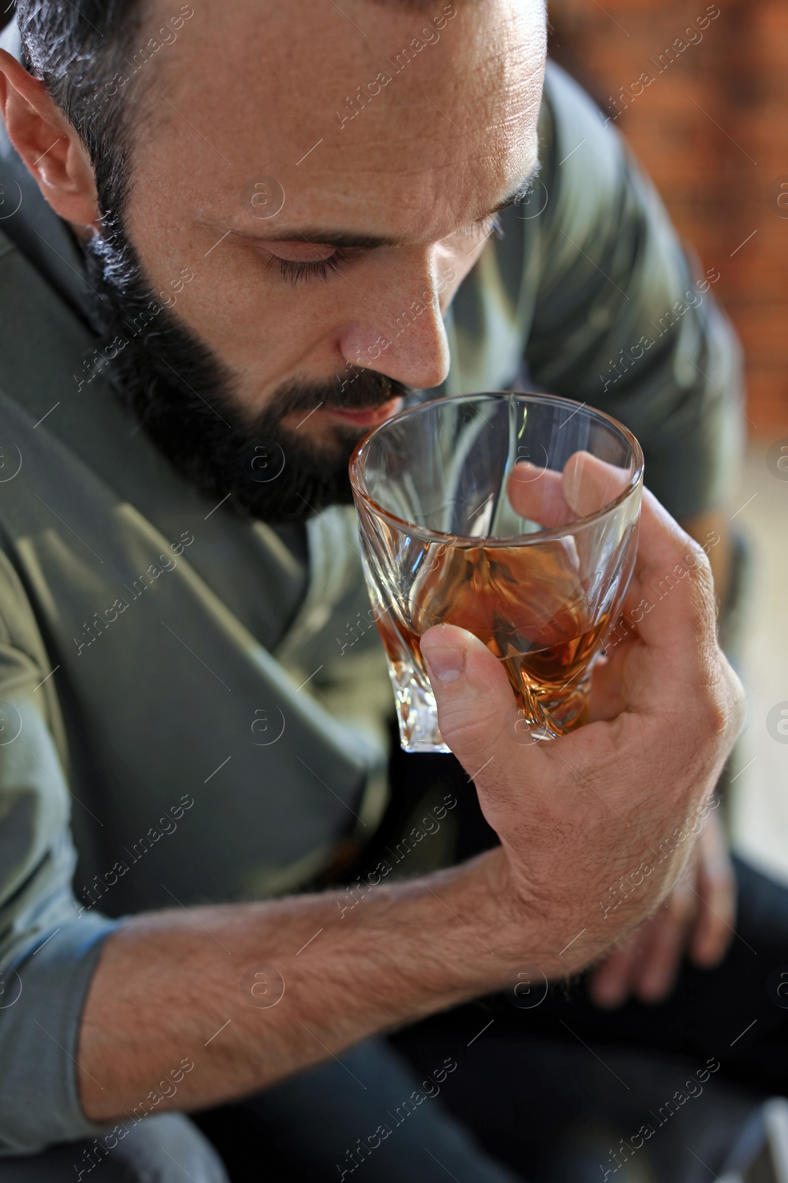 Photo of Handsome man holding glass of whiskey indoors