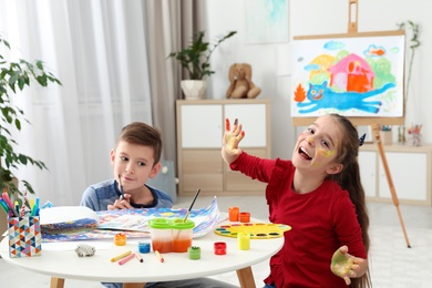 Happy children having fun with paints together at table indoors