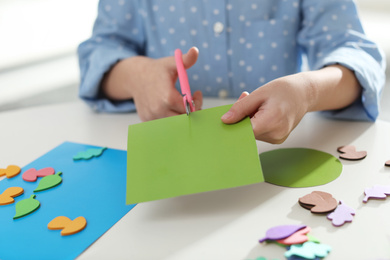 Photo of Little girl making greeting card at table indoors, closeup. Creative hobby