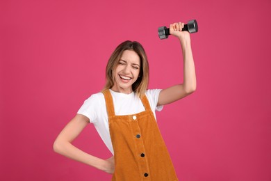 Woman with dumbbell as symbol of girl power on pink background. 8 March concept