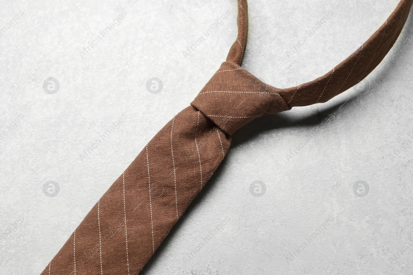 Photo of One striped necktie on light textured table, above view