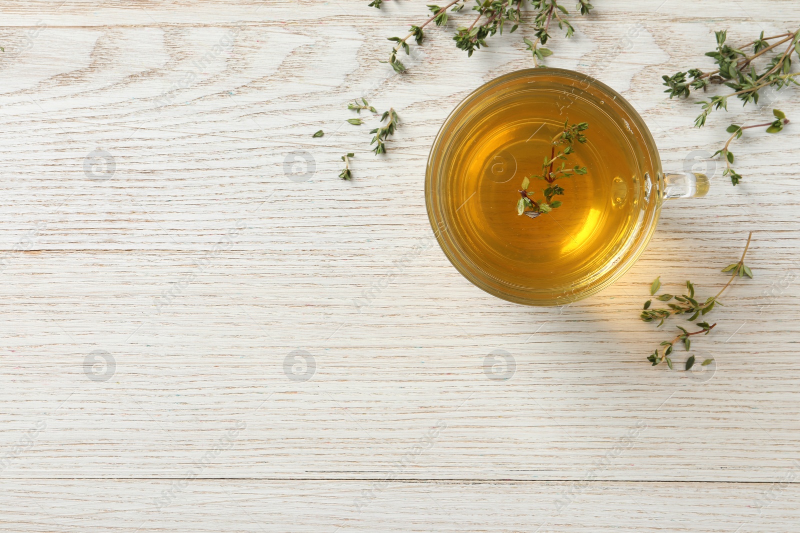 Photo of Aromatic herbal tea with thyme on white wooden table, flat lay. Space for text