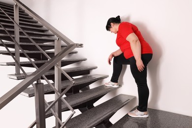Photo of Tired overweight mature woman running upstairs indoors