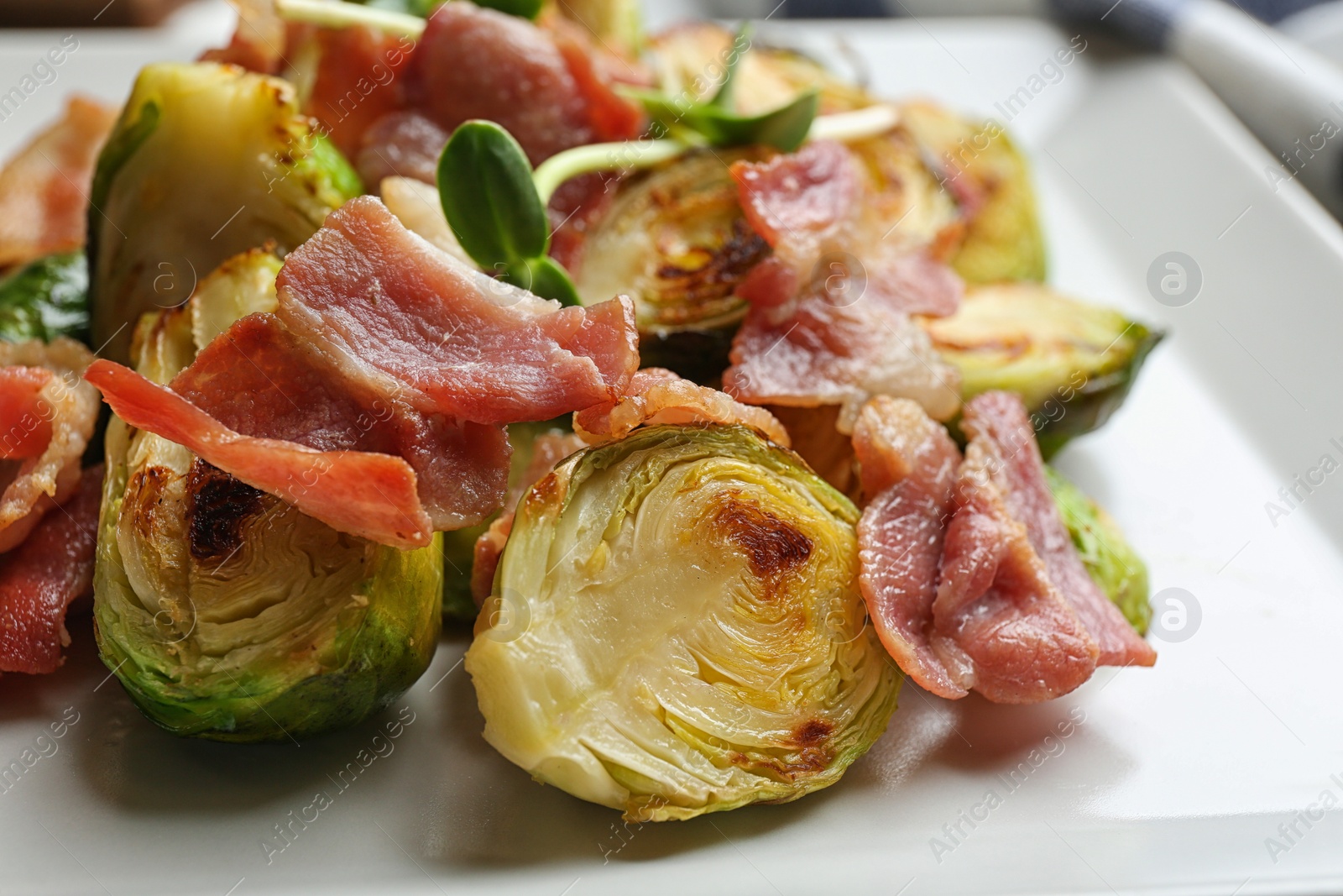 Photo of Delicious roasted Brussels sprouts with bacon on plate, closeup