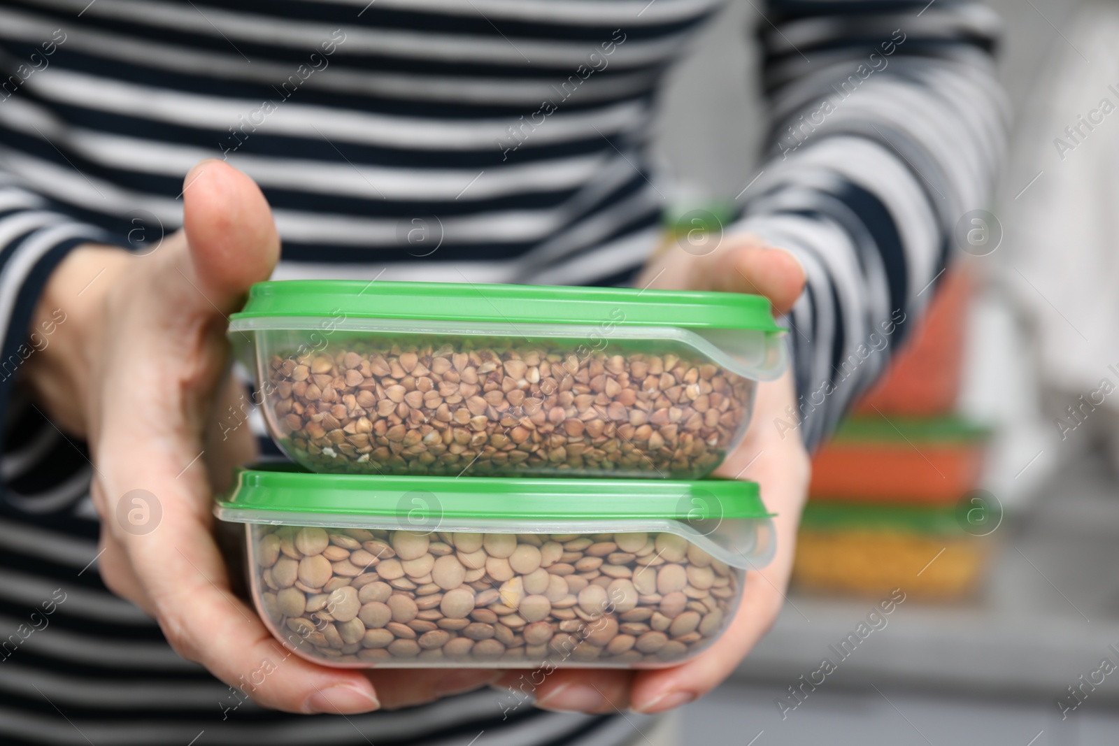 Photo of Woman with plastic containers of raw buckwheat and peas indoors, closeup. Food storage