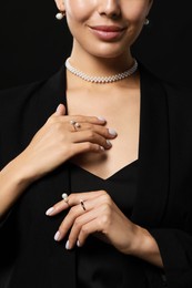 Photo of Young woman with elegant pearl jewelry on black background, closeup