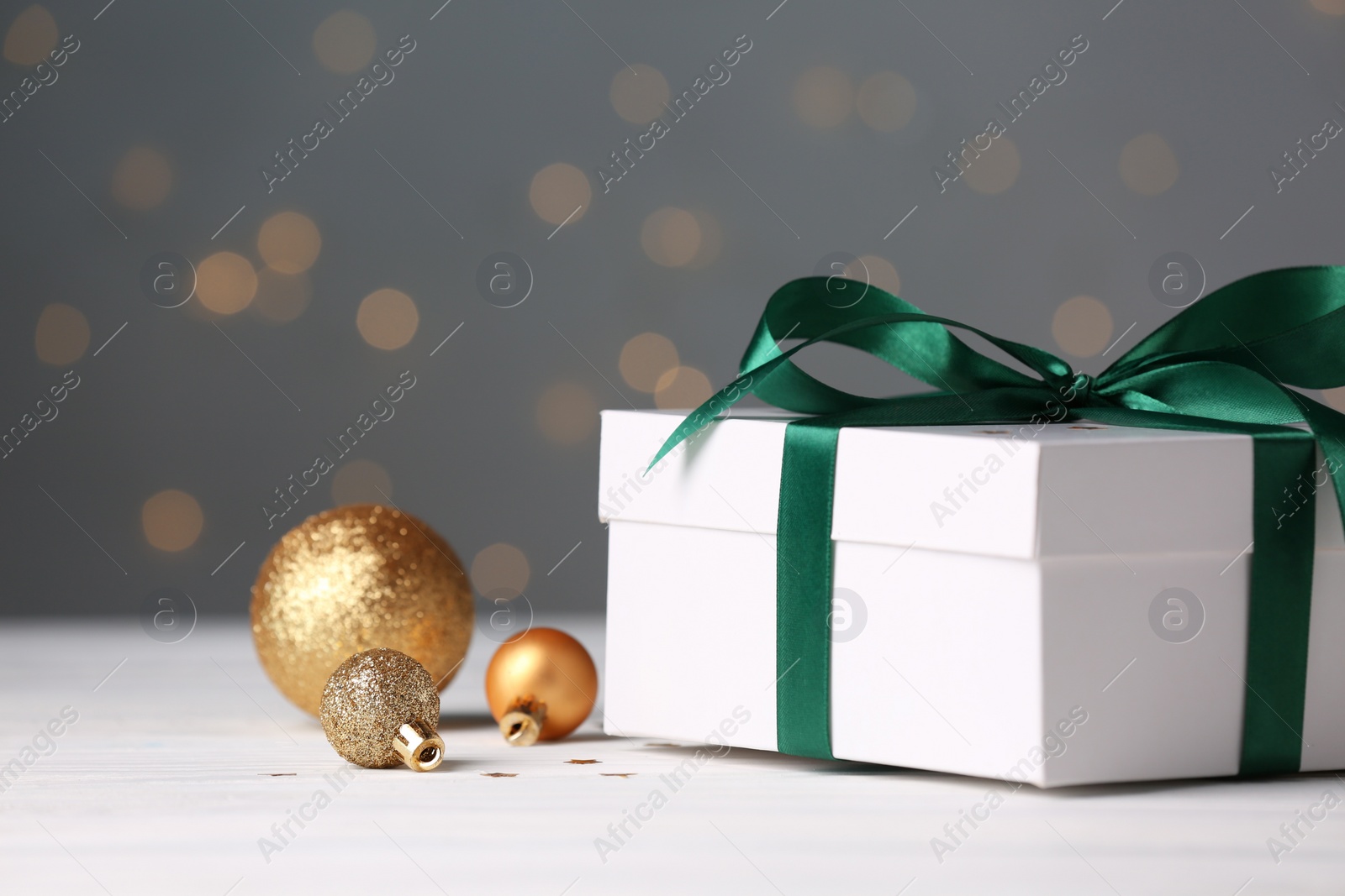 Photo of Gift box and Christmas decor on white wooden table. Space for text