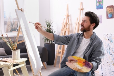 Man painting in studio. Using easel to hold canvas