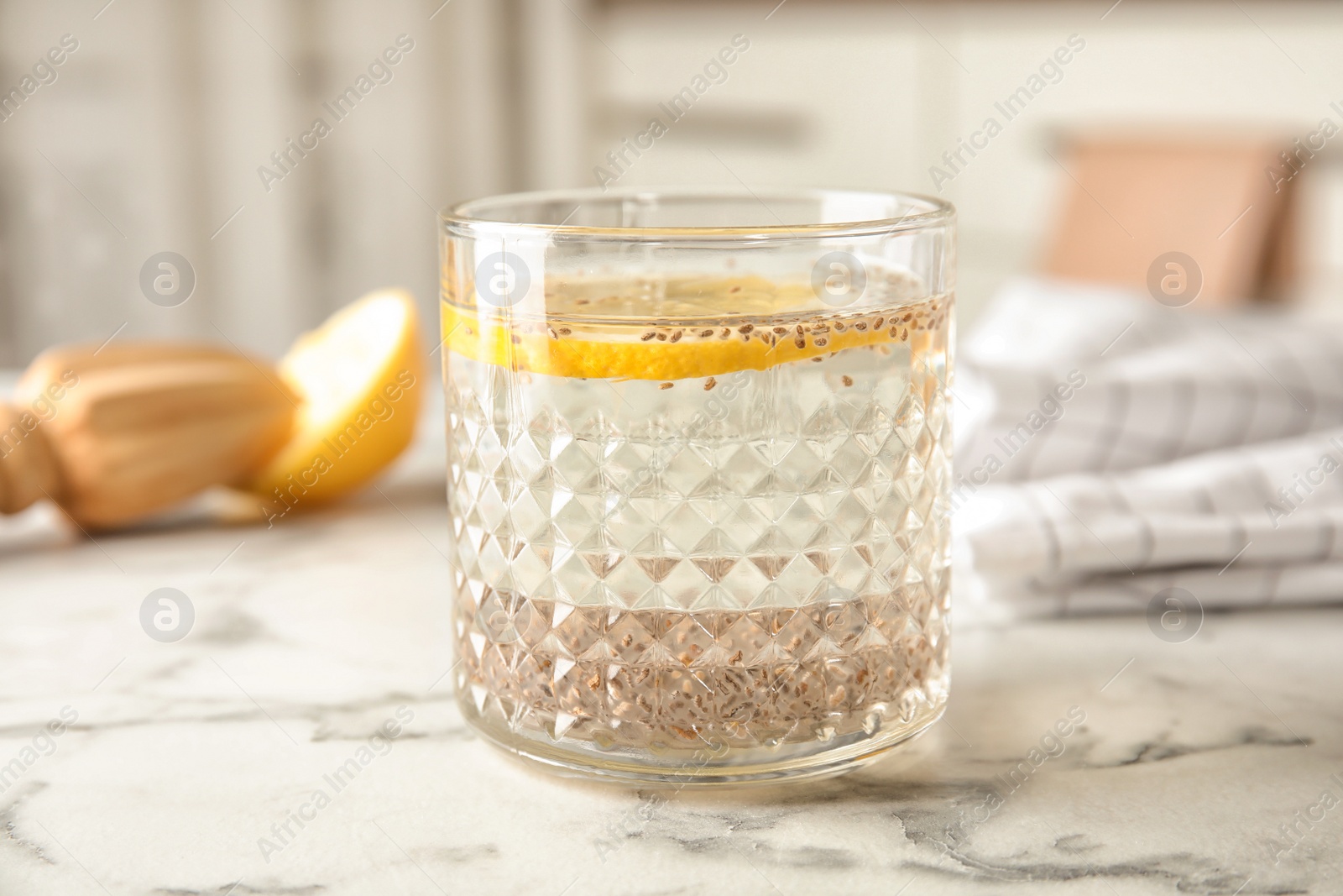 Photo of Glass of water with chia seeds on table against blurred background