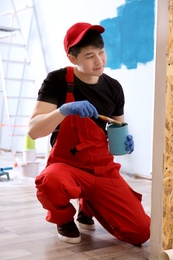 Male decorator painting wall with brush indoors