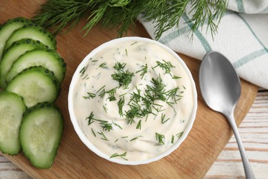 Photo of Tasty creamy dill sauce and ingredients on white wooden table, flat lay