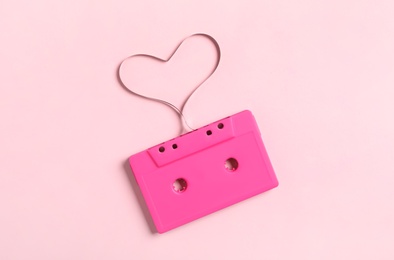Photo of Music cassette and heart made with tape on pink background, top view. Listening love song