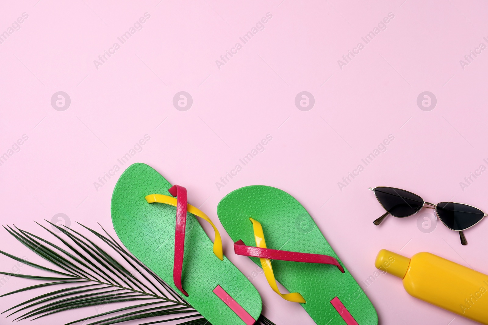 Photo of Stylish flip flops and beach objects on pink background, flat lay. Space for text