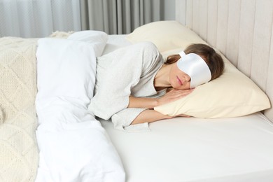 Woman with sleep mask in bed at home