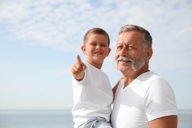 Photo of Grandfather with little boy on sea beach in summer