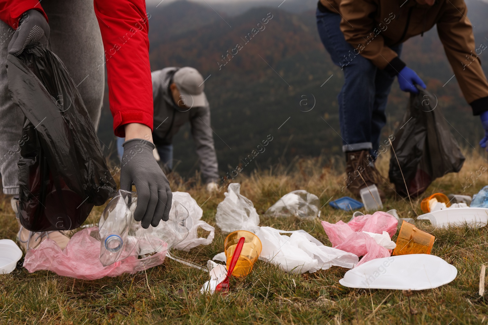 Photo of People with trash bags collecting garbage in nature, closeup