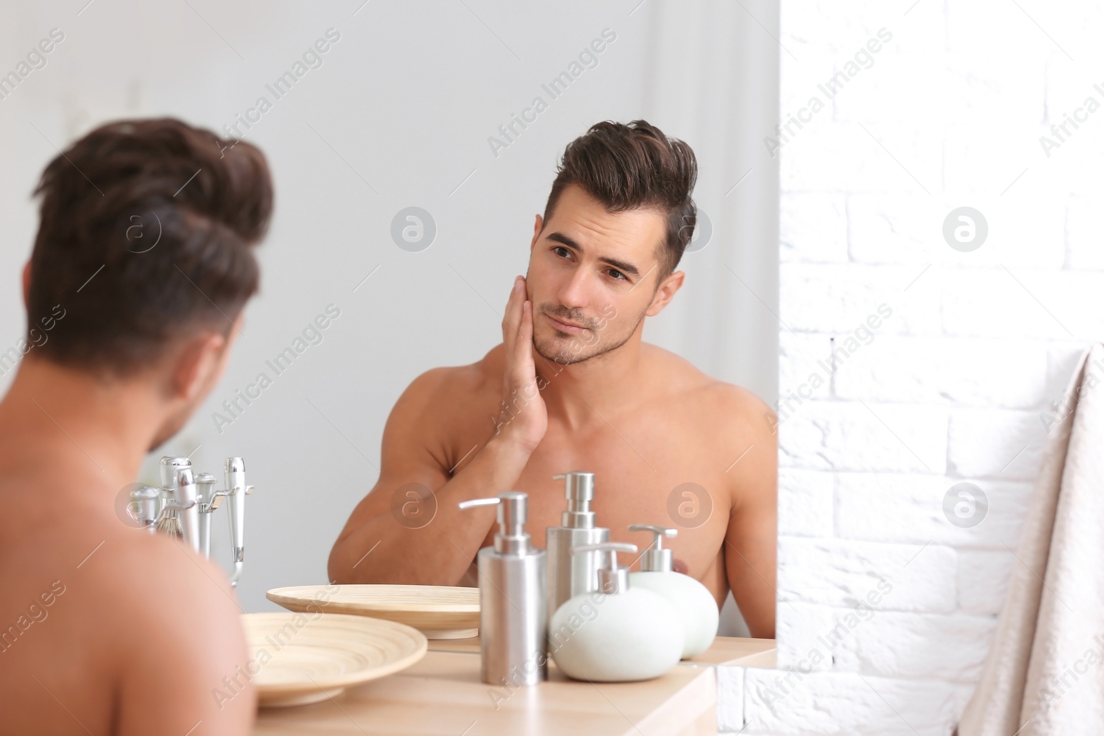 Photo of Young man with stubble ready for shaving near mirror in bathroom