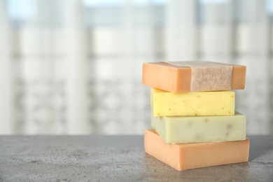 Stack of different handmade soap bars on table. Space for text