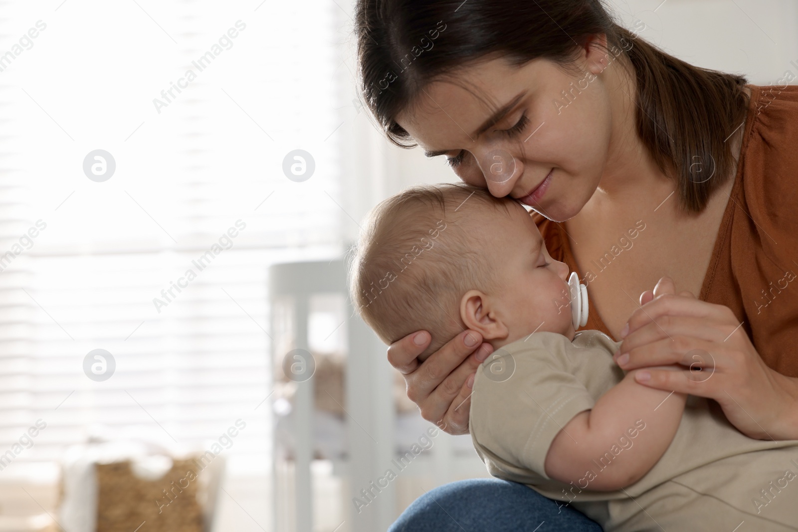 Photo of Happy young mother with her sleeping baby at home. Space for text