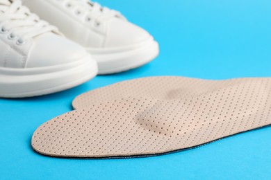Photo of Pair of insoles and shoes on light blue background, closeup