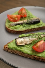 Photo of Delicious sandwiches with sprats, tomatoes, avocado puree and dill on table, closeup