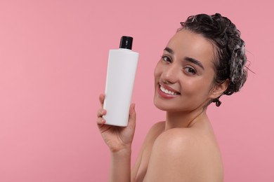 Washing hair. Portrait of beautiful happy woman with bottle on pink background. Space for text