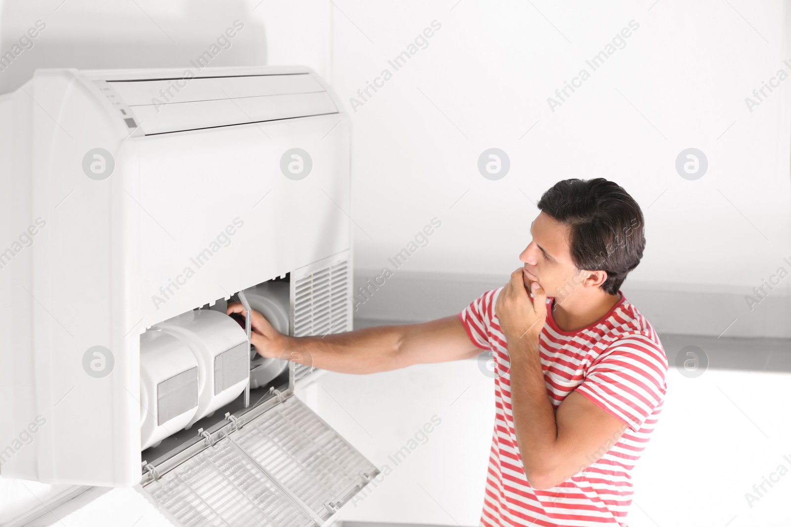 Photo of Young man fixing air conditioner at home