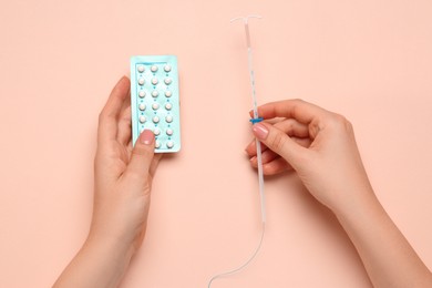 Photo of Woman with contraceptive pills and intrauterine device on beige background, top view. Choosing birth control method